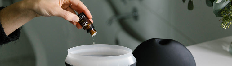 A person dropping essential oils into Saje Aroma Breeze diffuser