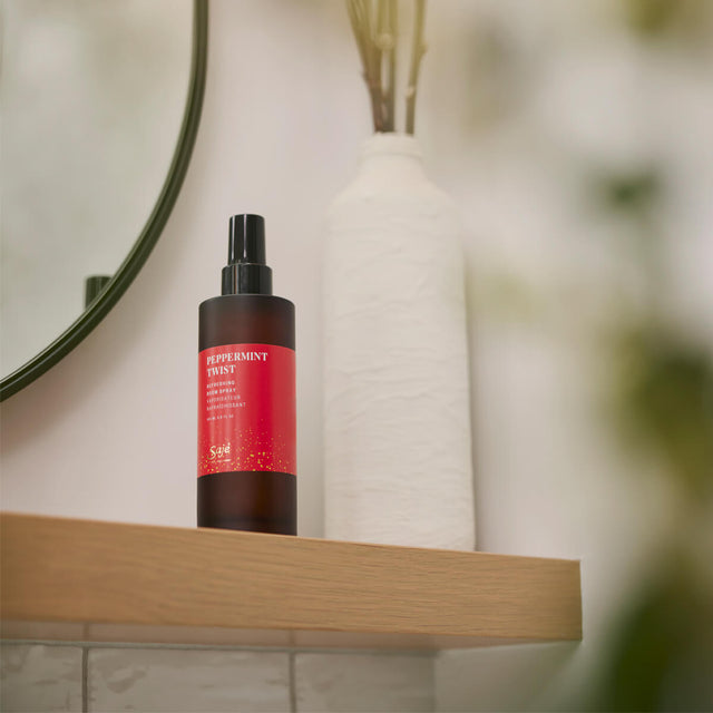 Peppermint twist room spray sitting on a wooden mantel beside a white vase