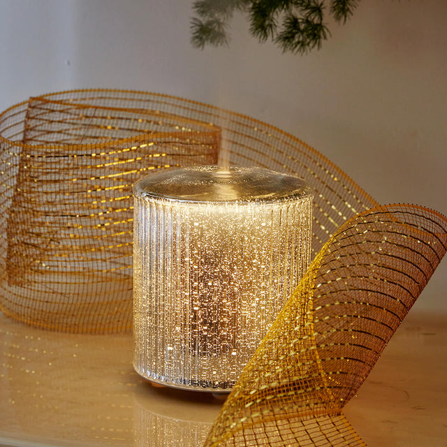 Aroma Lustre diffuser lit up with gold ribbon placed around it