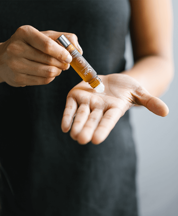 A person rolls a remedy roll-on on their palm.
