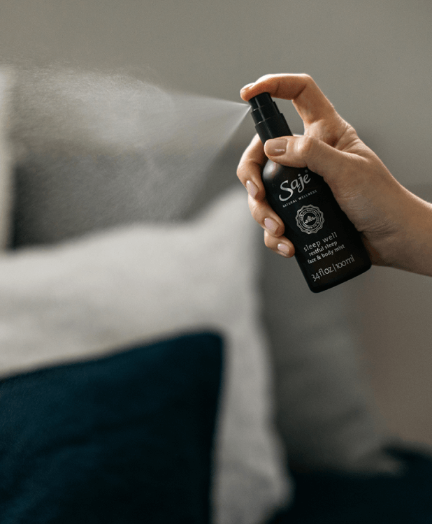A woman sleeping with a white Saje Aroma Om diffuser and diffuser blend on her bedroom side table.