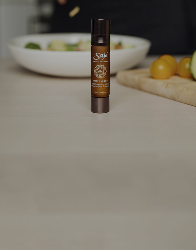 An Eater’s Digest remedy roll-on sits beside an assortment of vegetables in a kitchen.