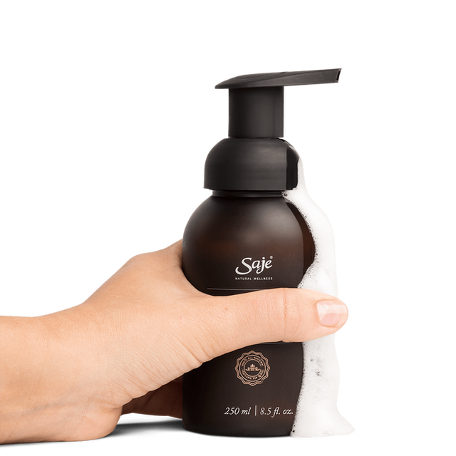 A person holding Safe Hands hand soap with the foam running down the side