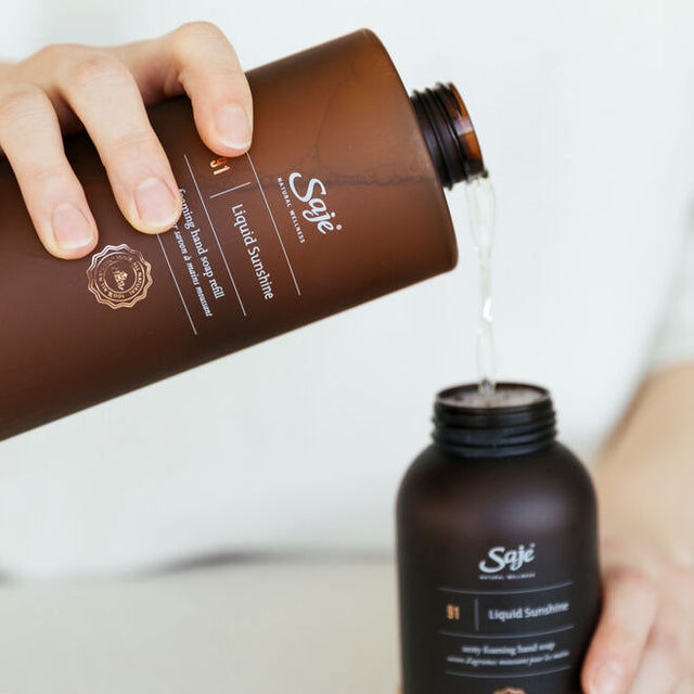 A person refilling their Liquid Sunshine dispenser with the foaming hand soap refill