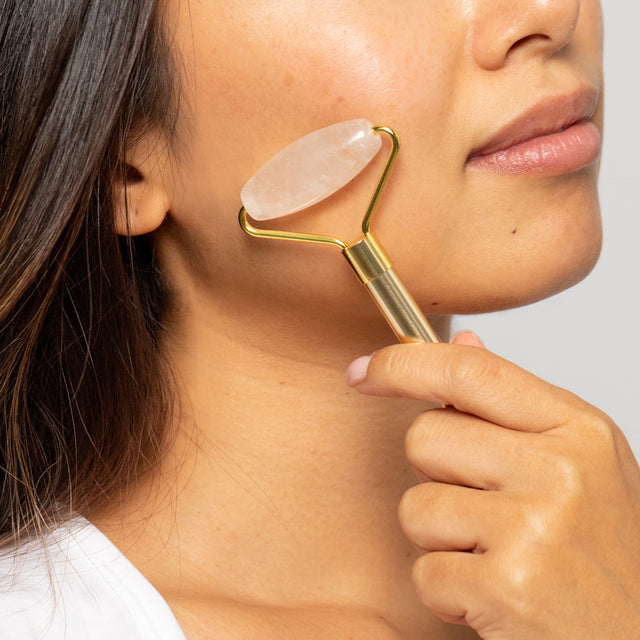 a woman using the crystal facial roller on her cheek