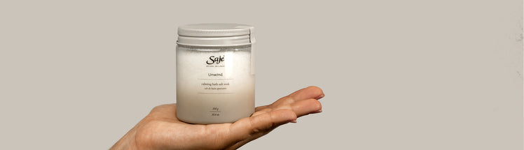 Saje Unwind bath salts displayed in a person's palm
