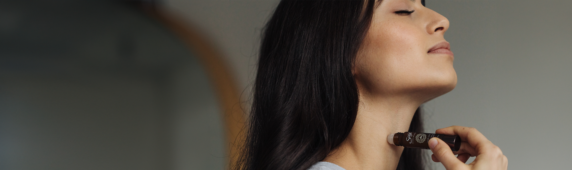 A woman applying immune roll-on to the neck