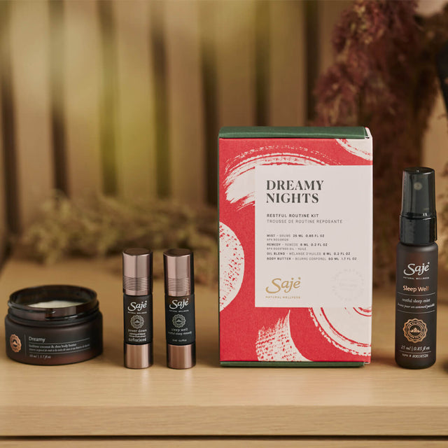 Dreamy body butter, sleep well mist, power down roll-on and sleep well roll-on with packaging sitting on a wooden table
