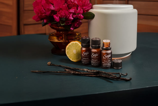 Persons sitting cross legged in the background, and diffuser and diffuser blend on a table