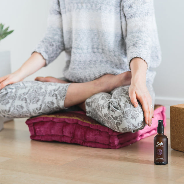 A person meditating with Yoga transition mist beside their yoga mat