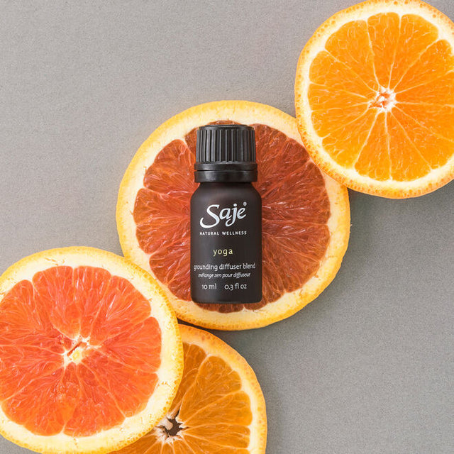 Yoga grounding diffuser blend 10ml bottle with cap on on top of grapefruit and orange slices