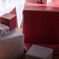 Gifts, wrapped in varying red and white wrapping paper, are arranged in a pile.