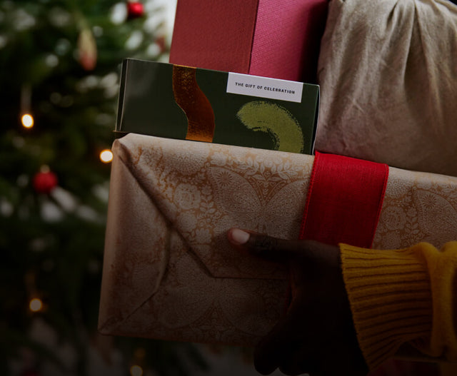 Saje packaging with a red bow and gift wrap, christmas tree in the background.