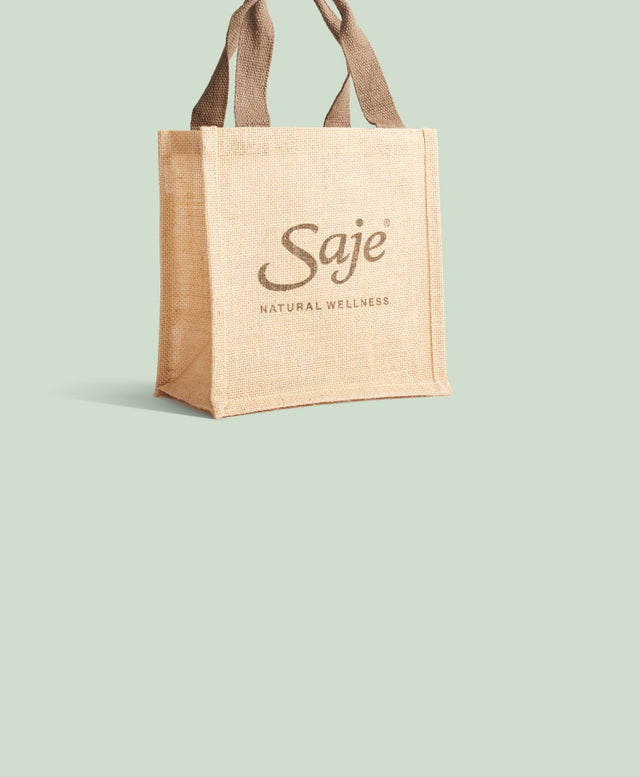 The iconic Saje jute shopping bag sits on a coloured background with the words “Yes, it’s back.”