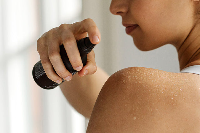 A person applying a mist to their shoulder