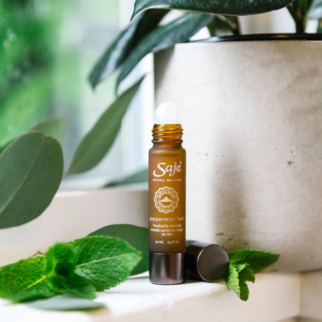 Saje Wellness Peppermint Halo Roll-On on desk with greenery