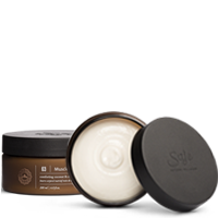 An opened container of Saje body butter.