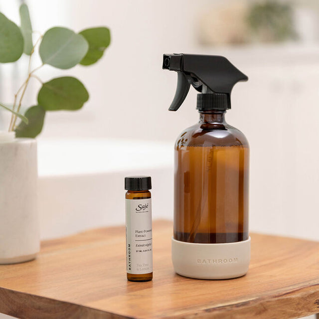 Bathroom cleaner styled on a wooden table with a vase of eucalyptus leaves