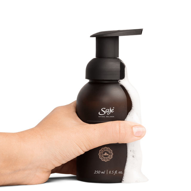  A person holding Safe Hands hand soap with the foam running down the side
