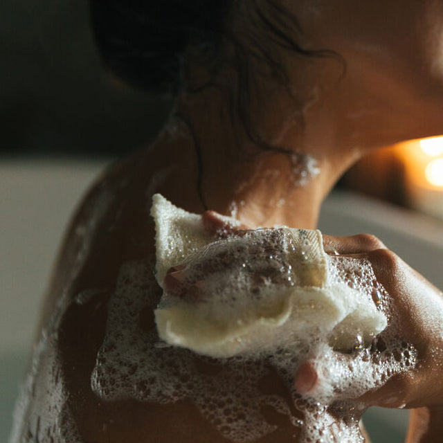 a woman with a wet and bubble soaked jute and joy was pad in a bath