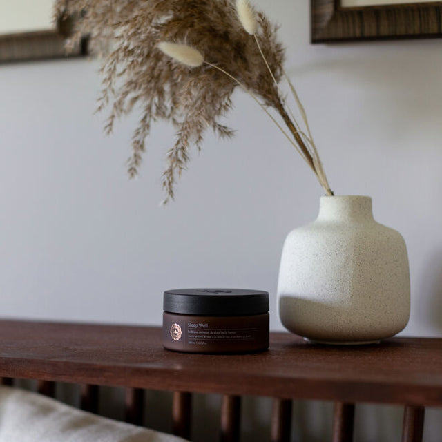 Sleep Well body butter in the home next to a vase and dried florals