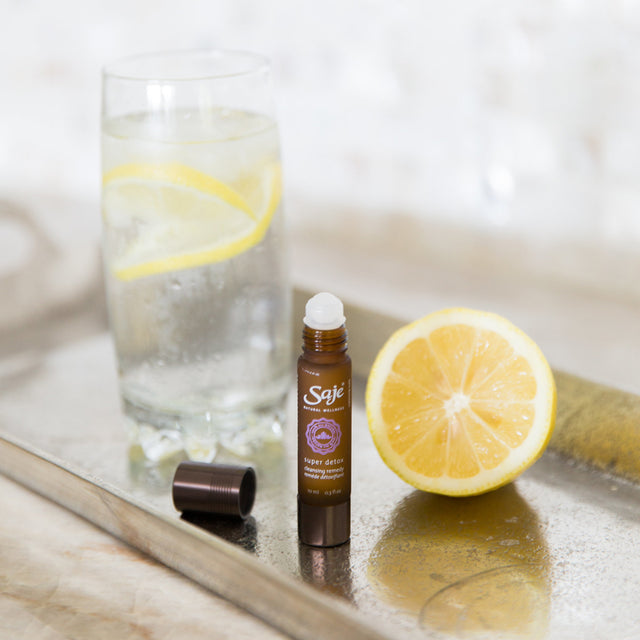 super detox cleansing remedy roll-on placed with lemon and water 