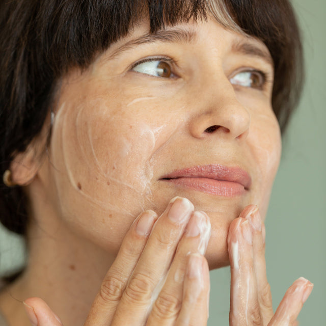 person applying True Dew Cream Cleanser on face