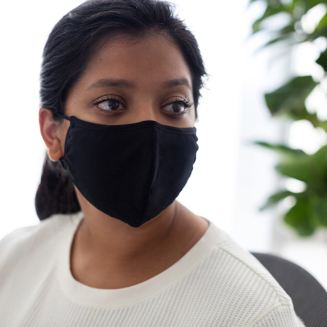 woman in a white sweater wearing the black face mask, covering from her nose to the bottom of her chin