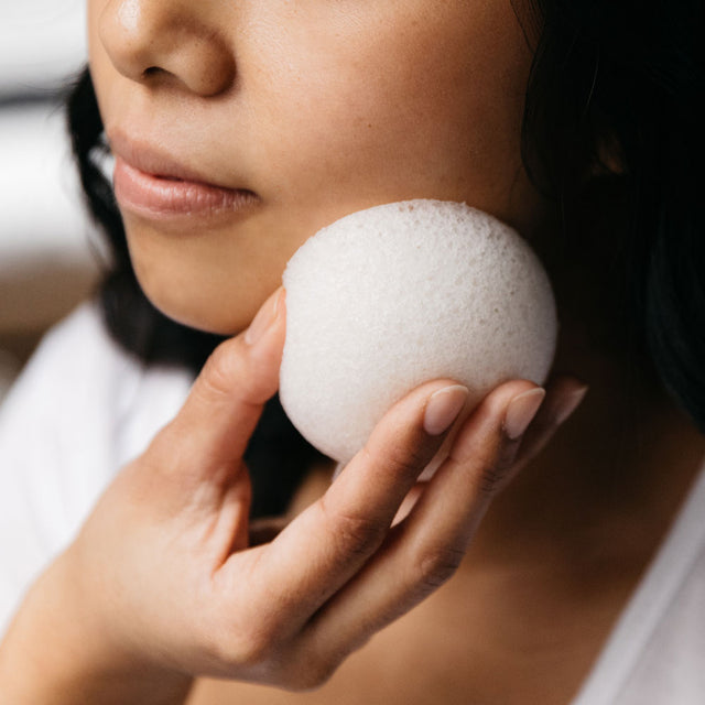 a woman using the Konjac hydrating vegetable fibre sponge directly on her face