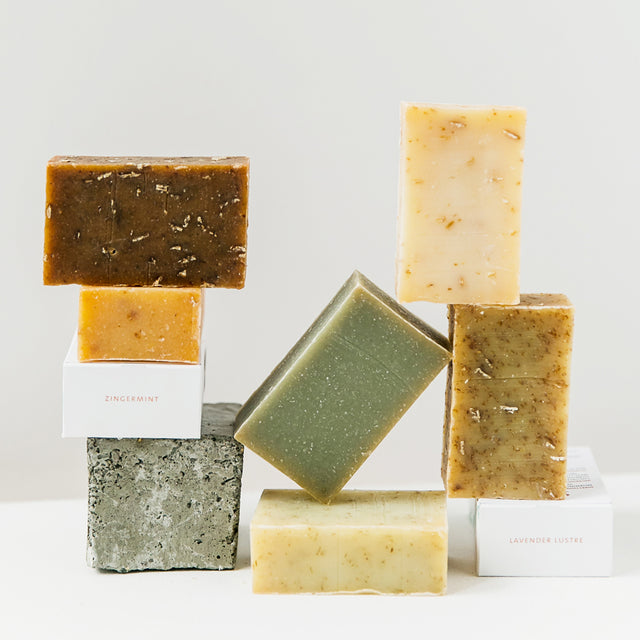 A collection of Saje cold-processed soaps on a white background