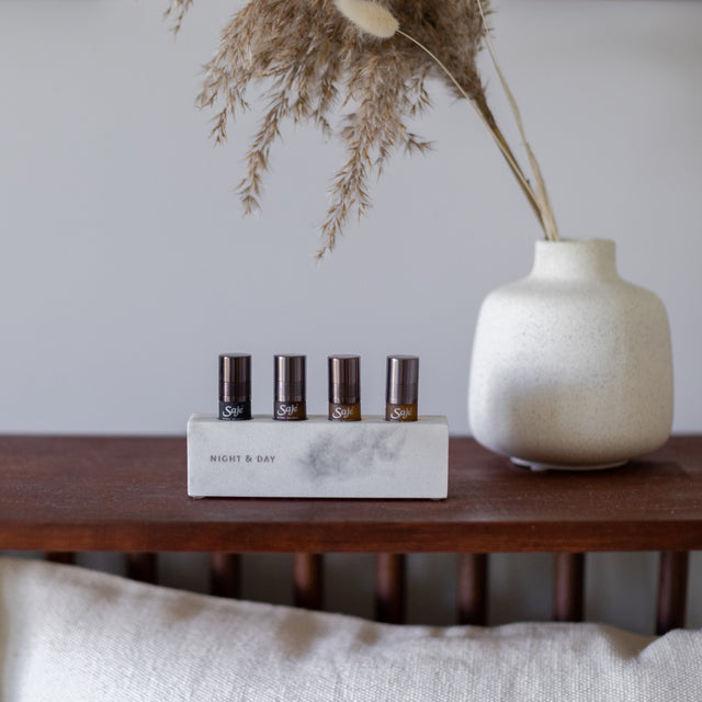 The 4 roll-ons in the Night & Day remedy bar on wooden table next to a vase with dried flowers 