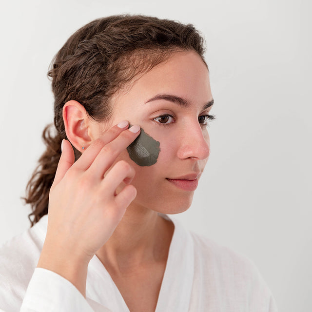 person applying Radiance Mode brightening clay mask to face