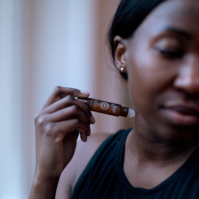 person applying Yoga 10 ml roll-on to neck